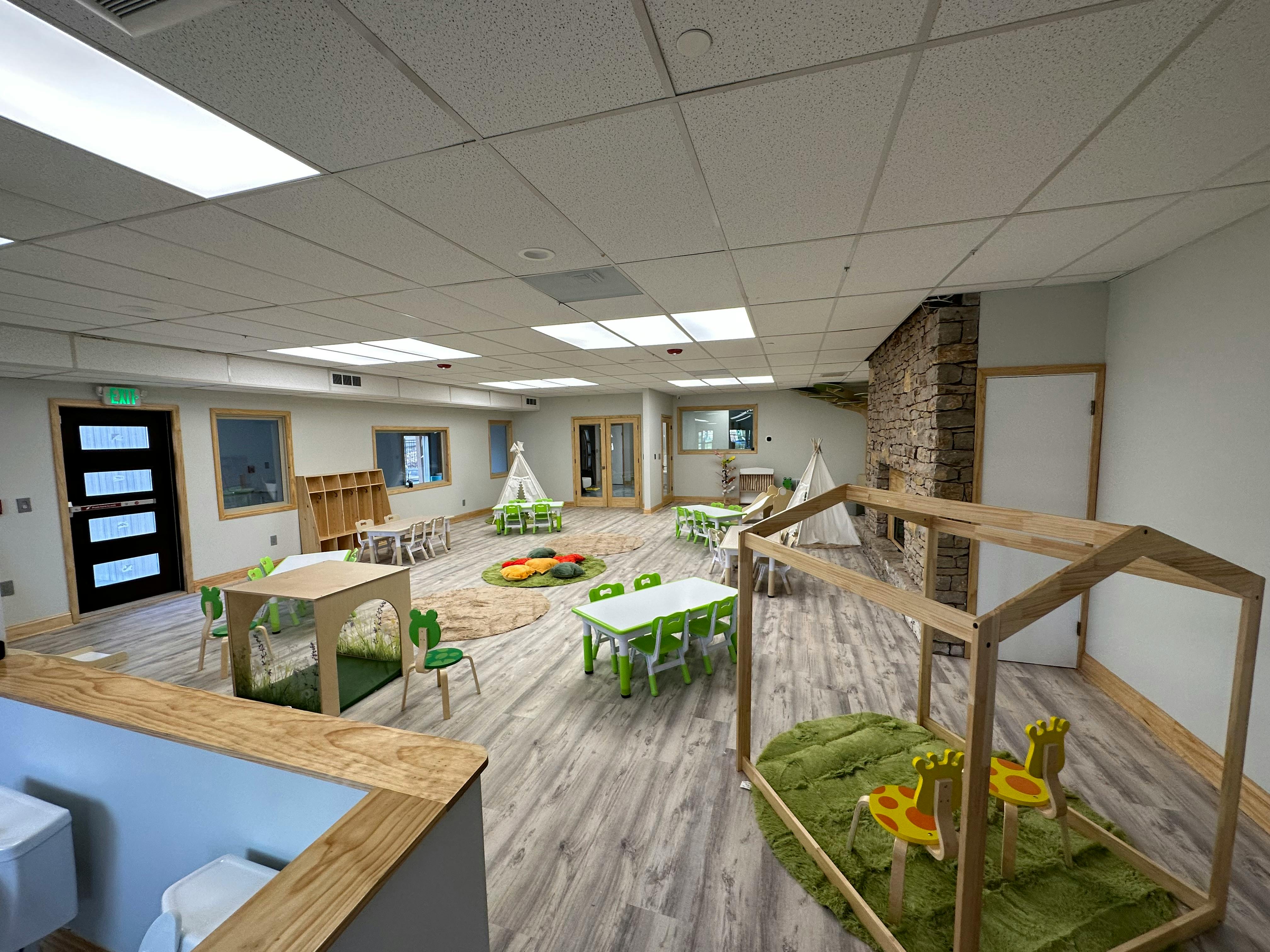 Empty classroom with small tables, chairs, and play structures