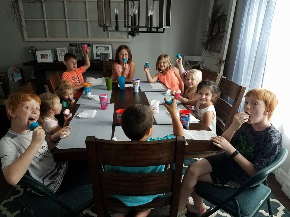 Children sitting around a table eating popsicles