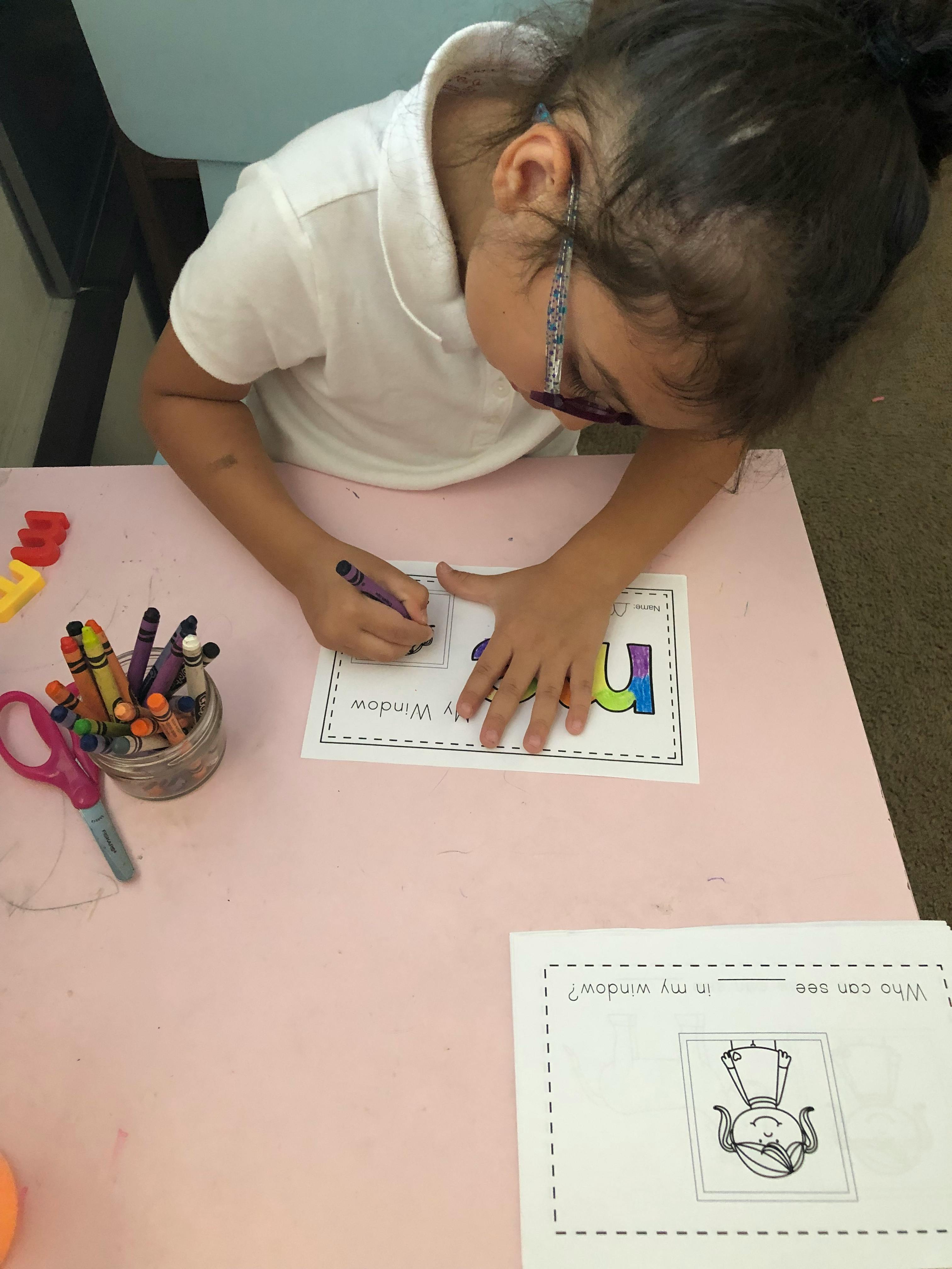 Child coloring a letter on a worksheet at a table