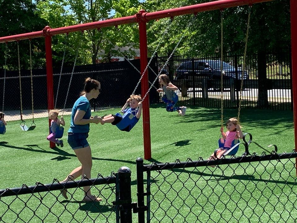 Person pushing a child on a swing at a playground