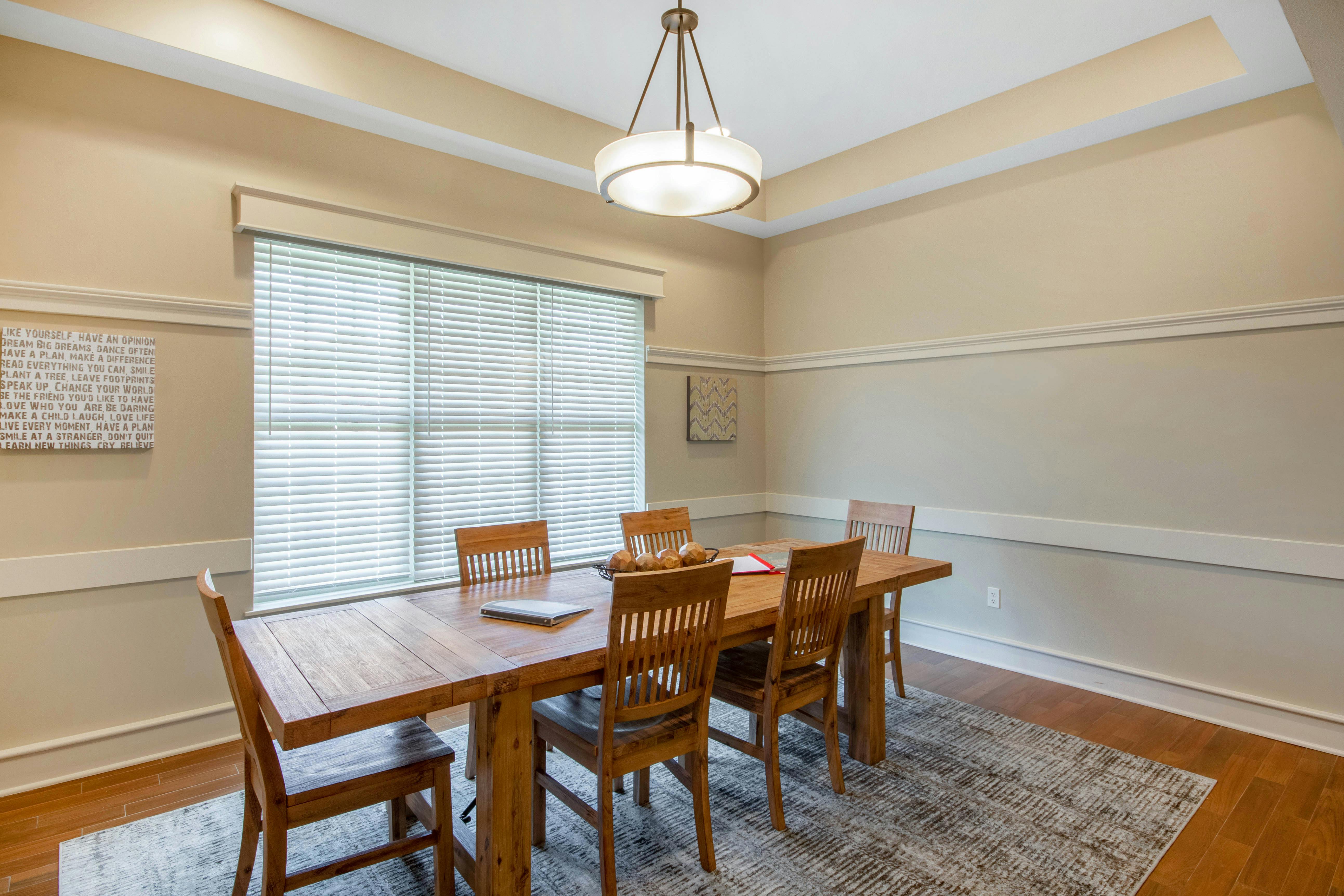 A wooden dining table with six chairs on a rug in a dining room