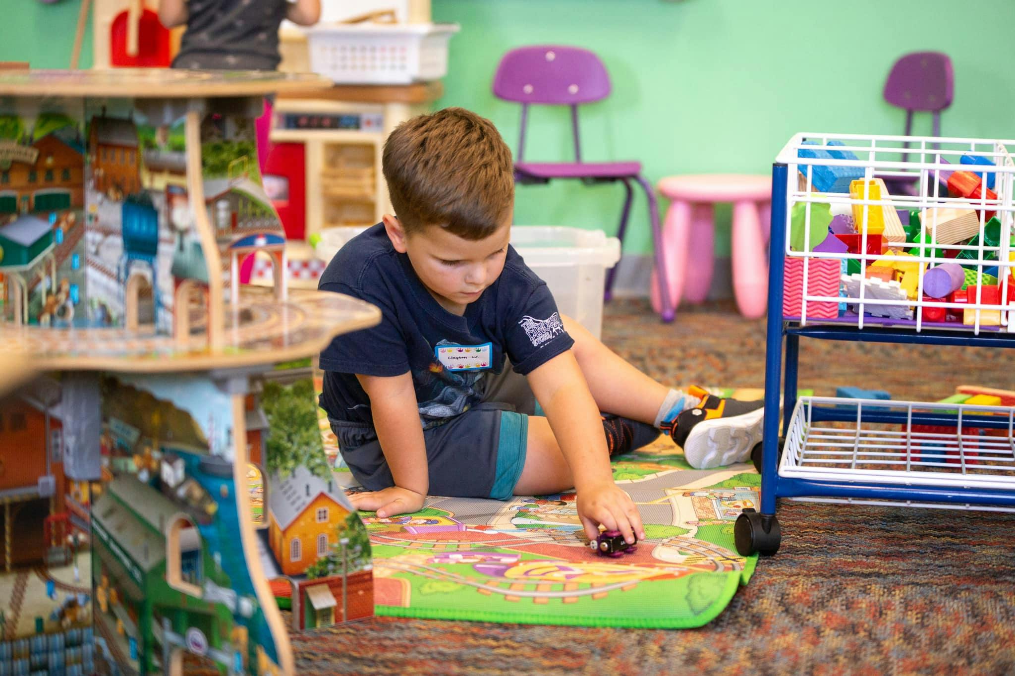 Child playing with a toy car on a mat