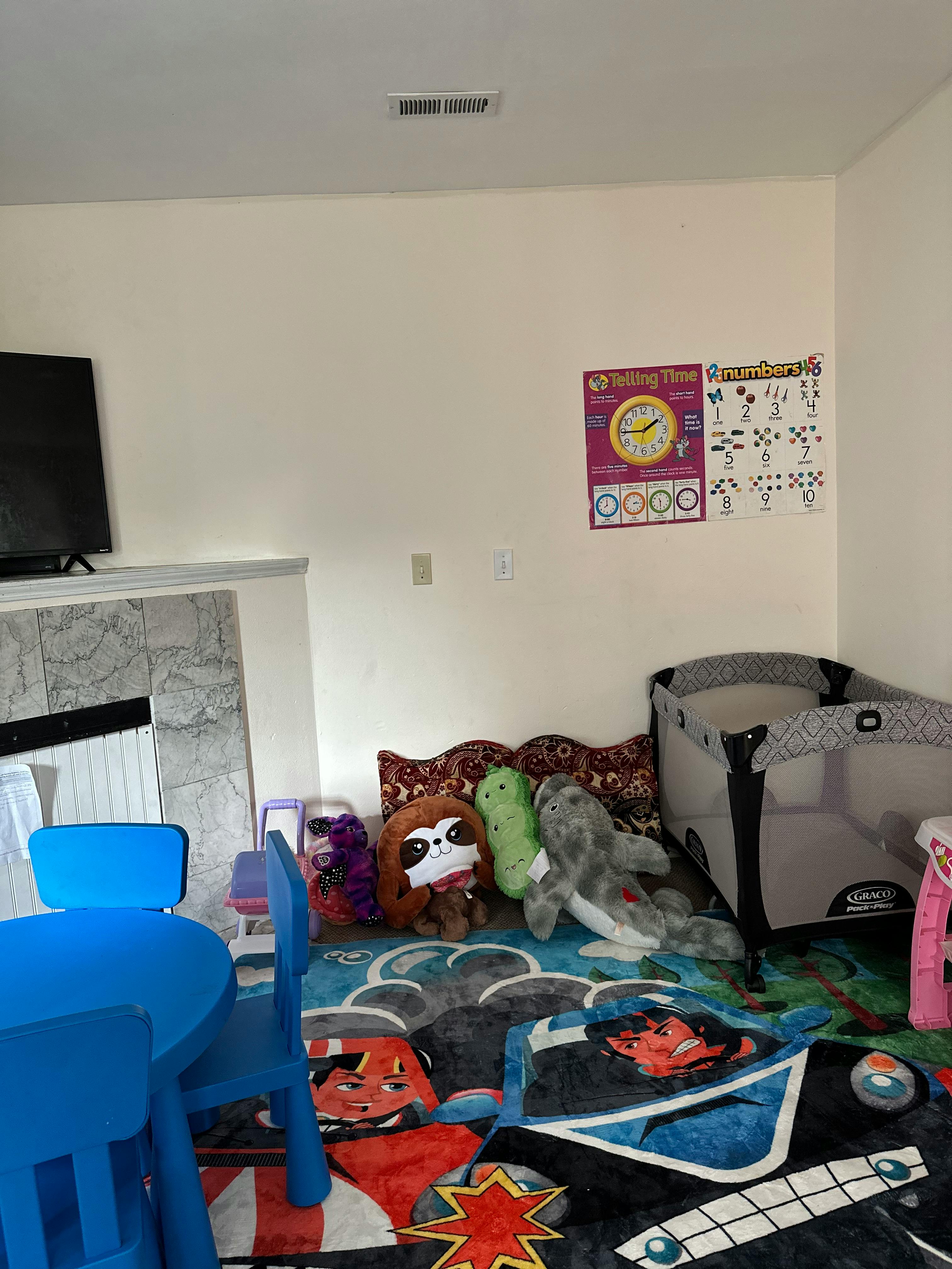 Playroom with a blue table and chairs, stuffed animals, and a playpen