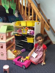 Child playing with a toy car and dollhouse