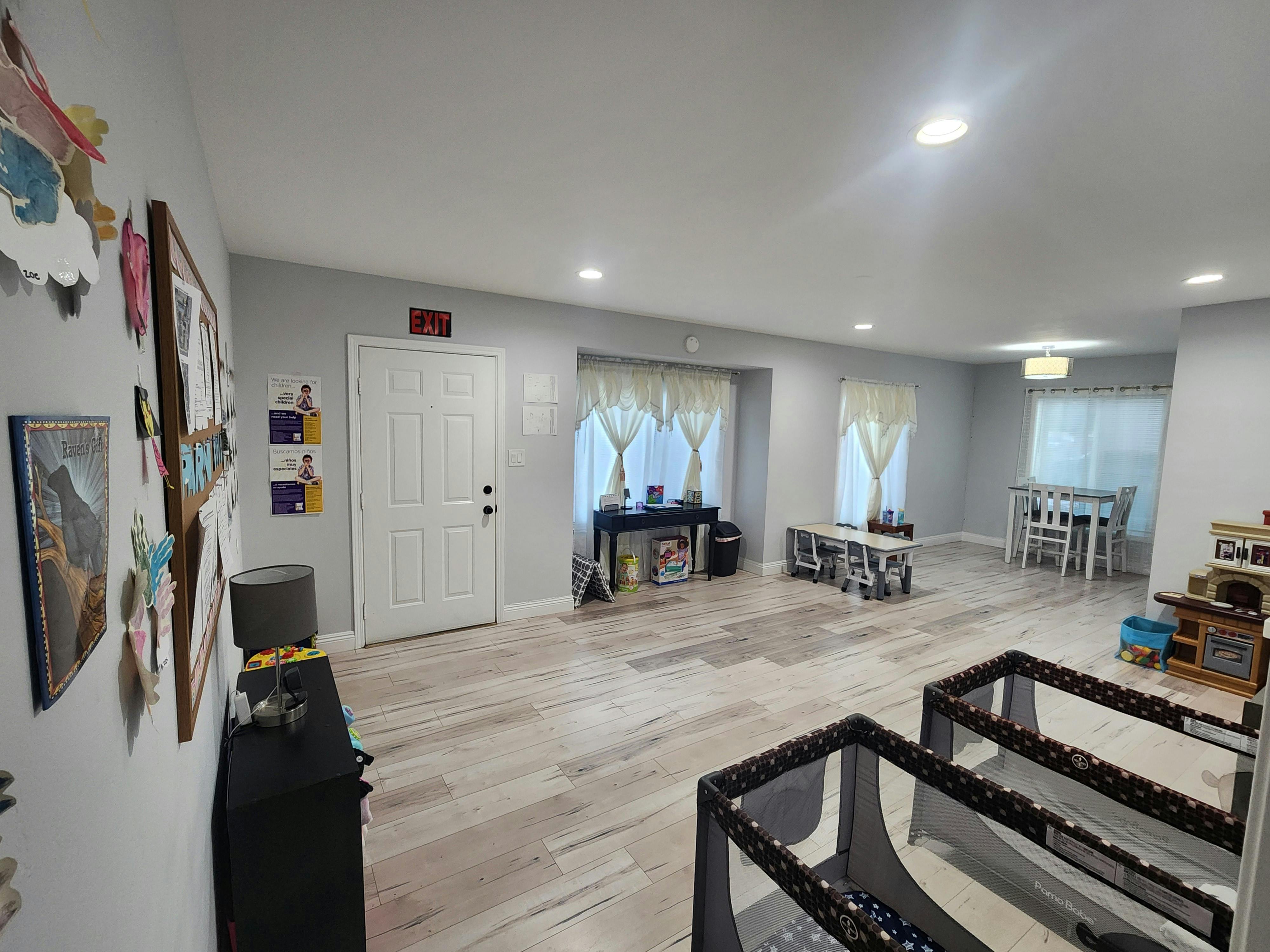 Room with light wood floor, white walls, and two playpens