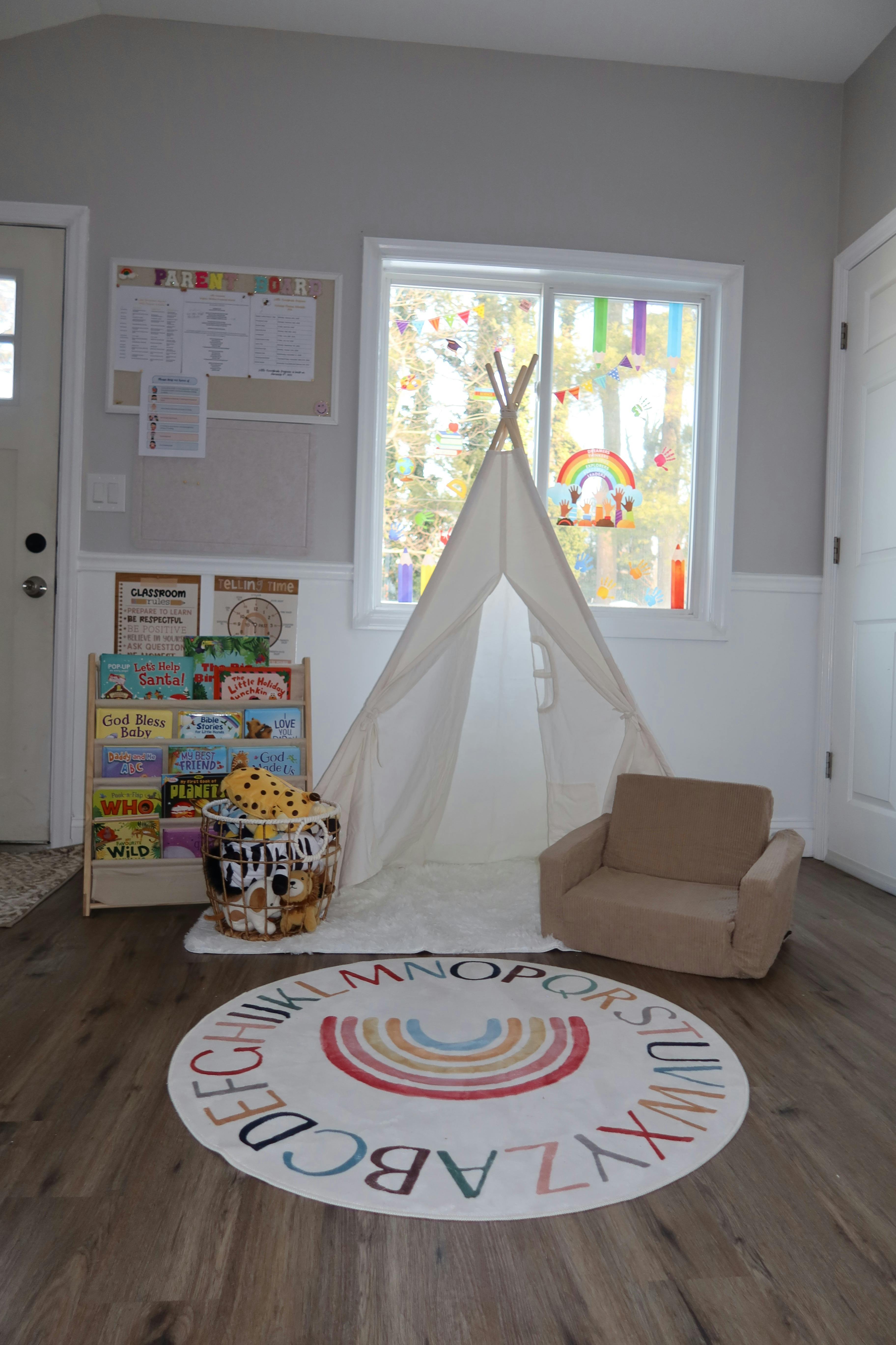 Children's playroom with a teepee, bookshelf, small chair, and alphabet rug