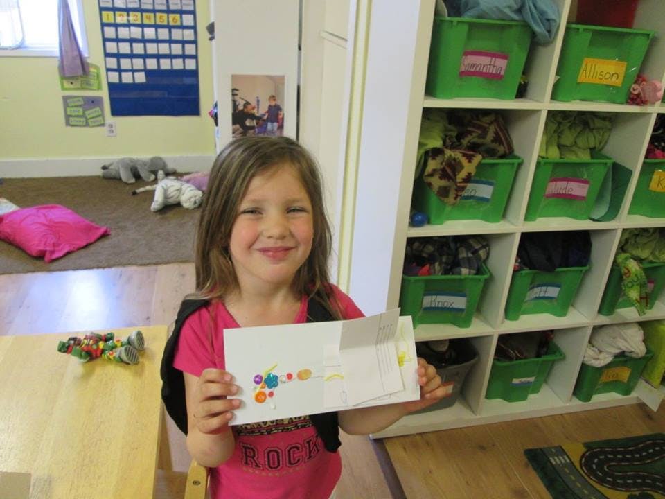 Child holding up a piece of paper with colorful dots