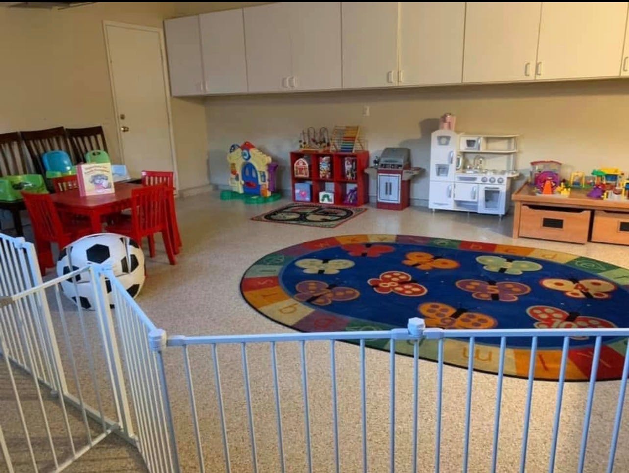 Child's playroom with gate, play kitchen, red table, and butterfly rug