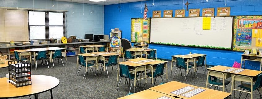 Empty classroom with desks and chairs facing a whiteboard