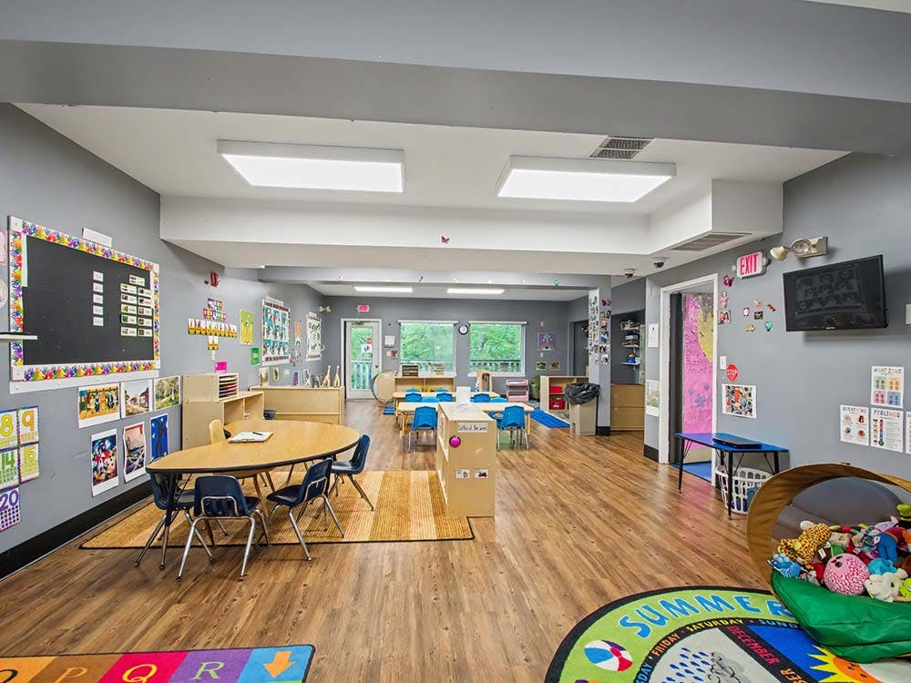 Colorful classroom with small tables and chairs, a blackboard, and educational posters