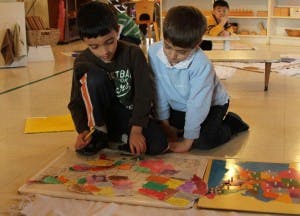 Two children kneeling on floor working on puzzles