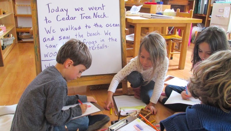 Children writing and drawing on the floor in a classroom