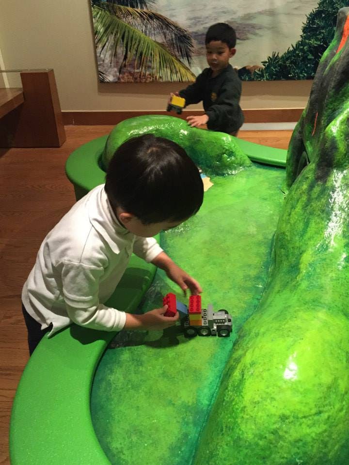 Two children playing with toys on a green sculpted surface