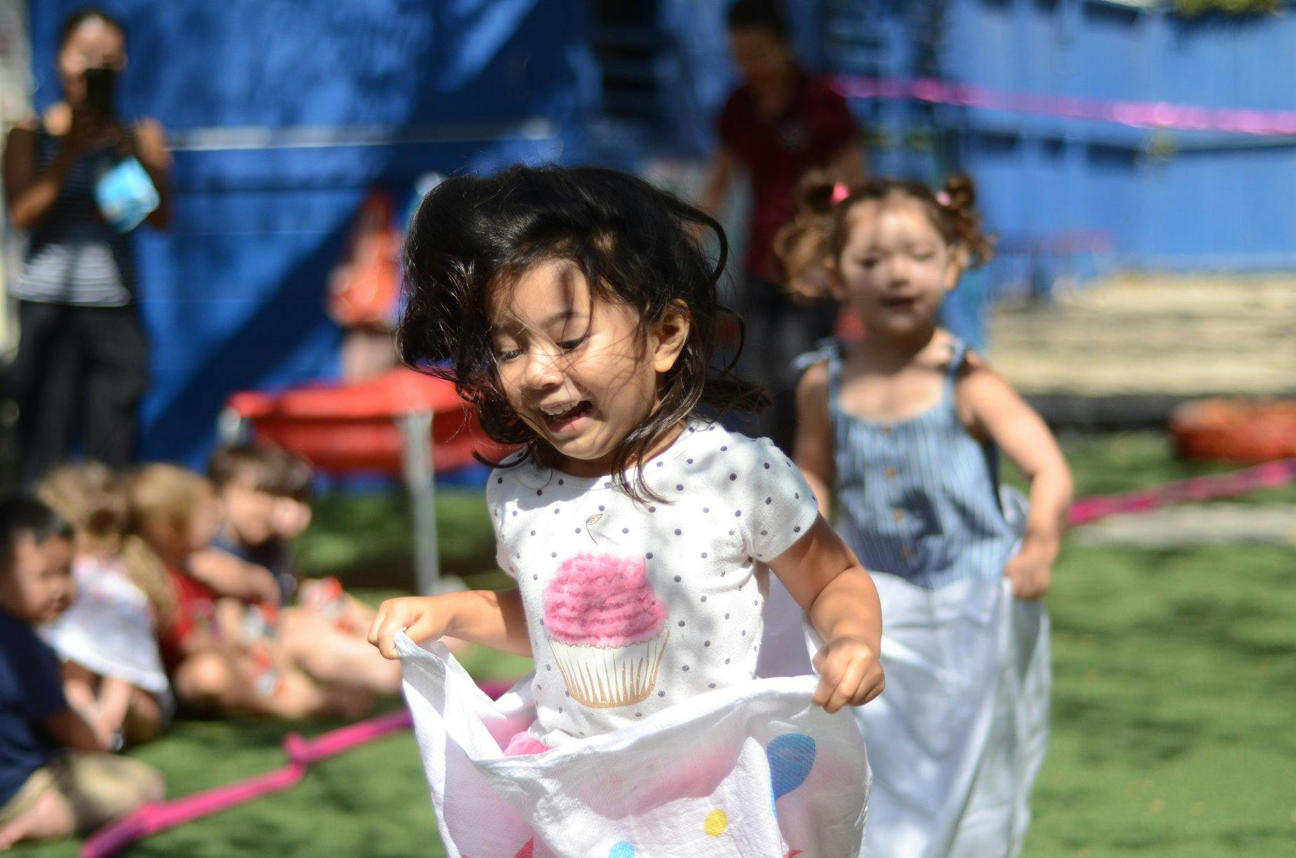 Child in a sack race, another child behind