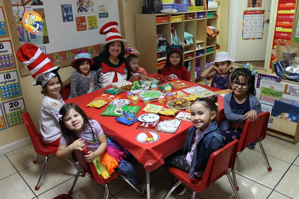 Adult and children sitting around a table with party supplies