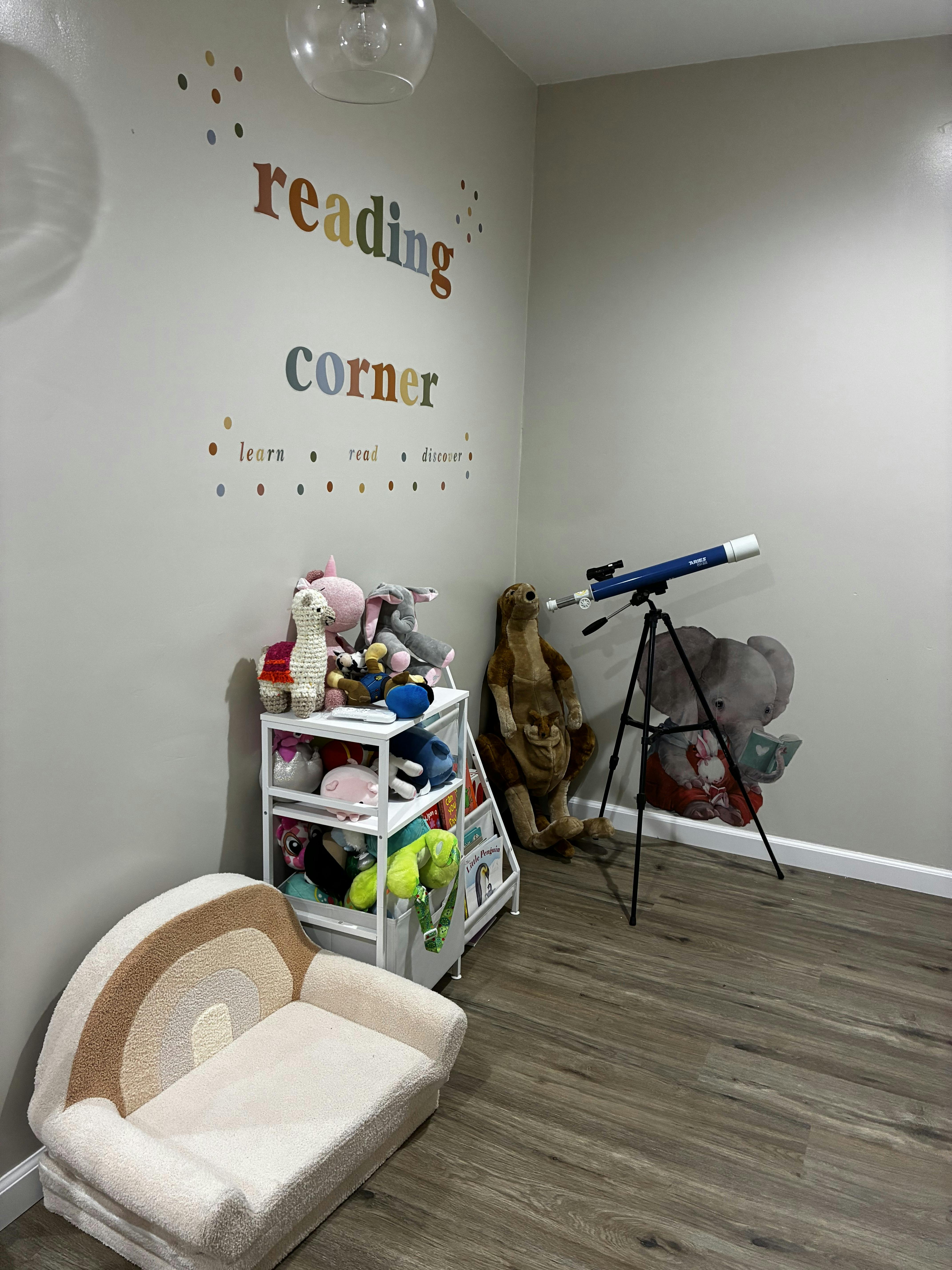 Children's reading corner with a rainbow chair, storage unit with stuffed animals