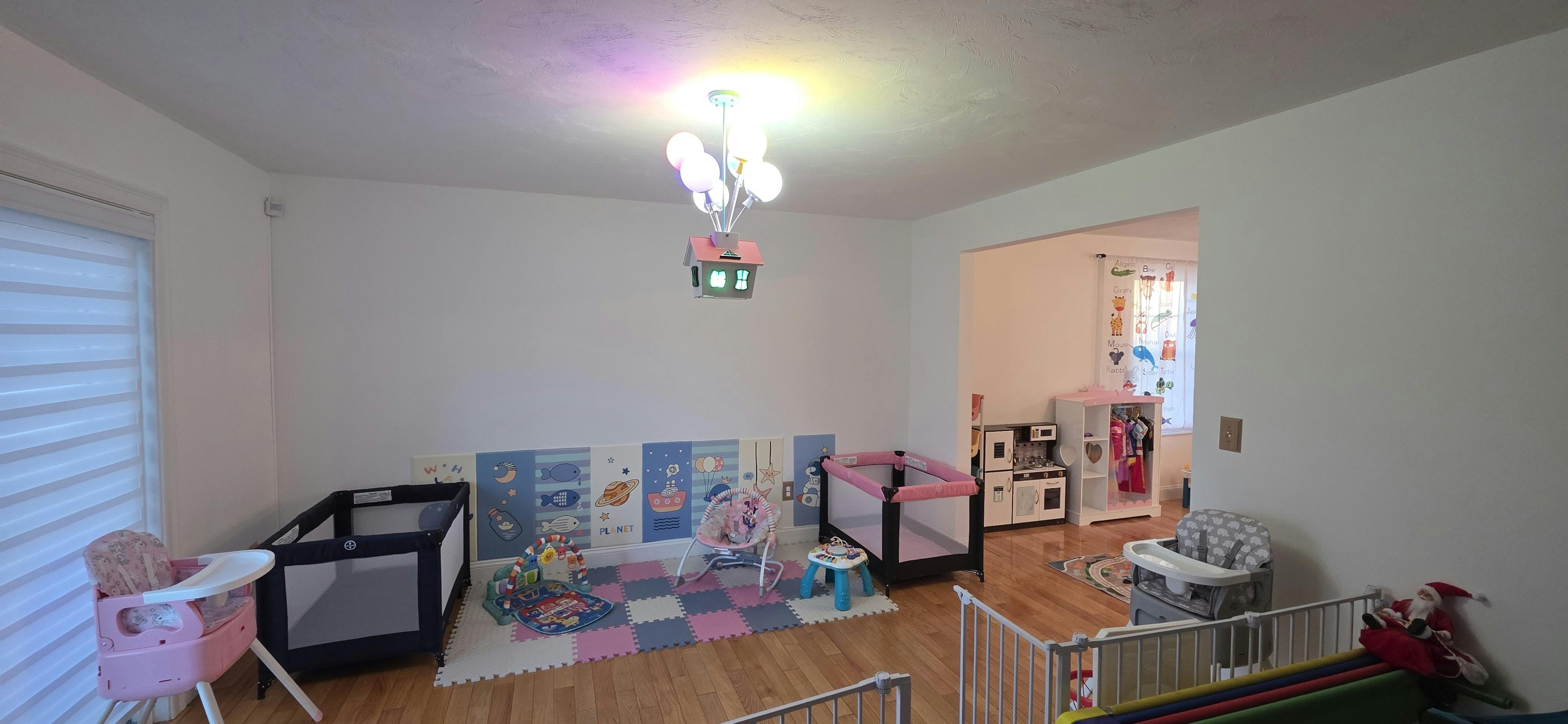 playroom with two cribs, infant rocker, and play kitchen