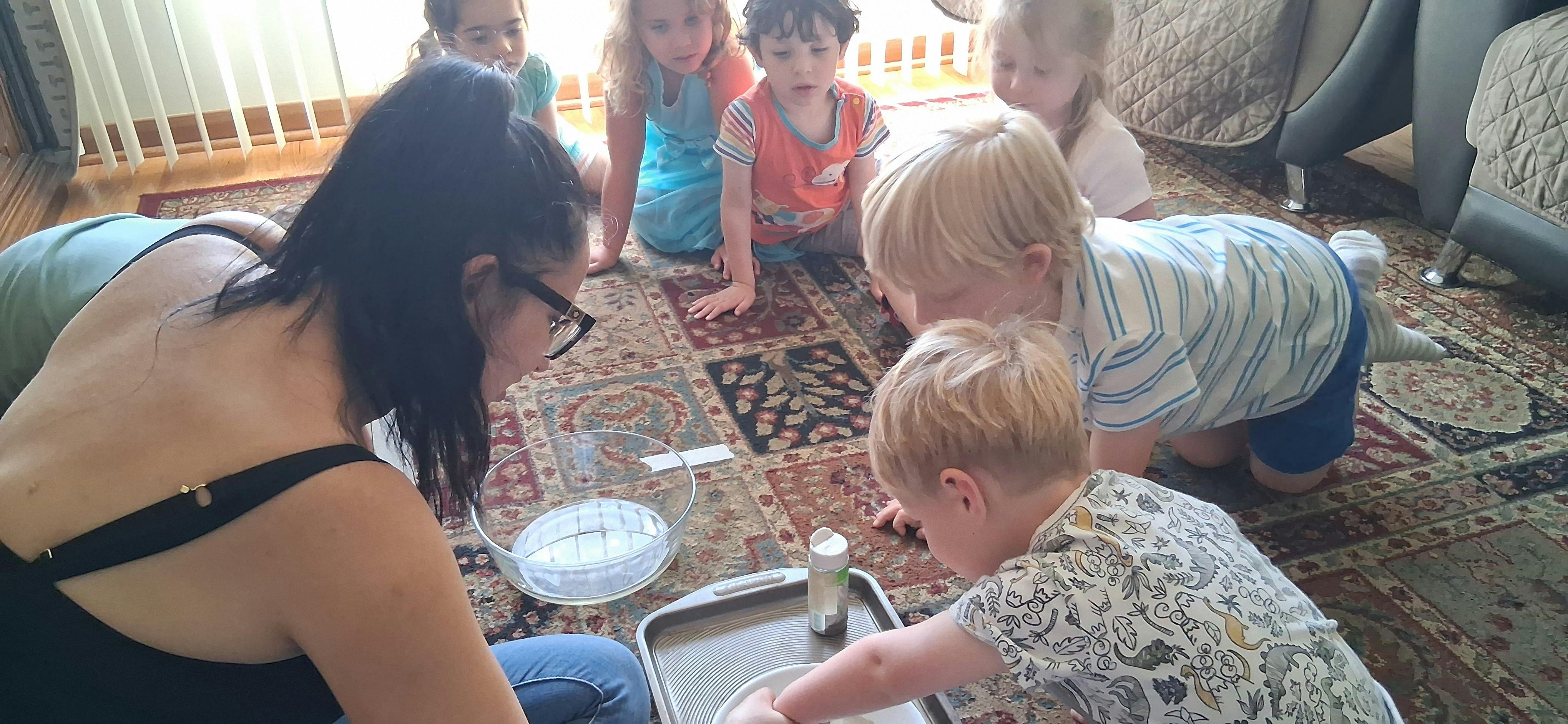 Person and multiple children on floor looking at tray