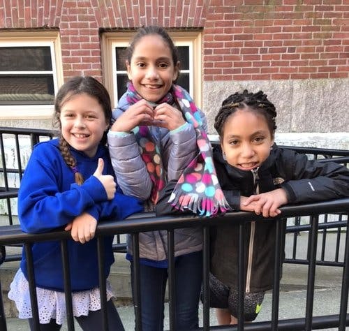 Three children leaning on a black railing