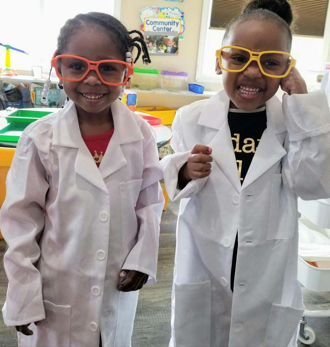 Two children wearing lab coats and oversized glasses