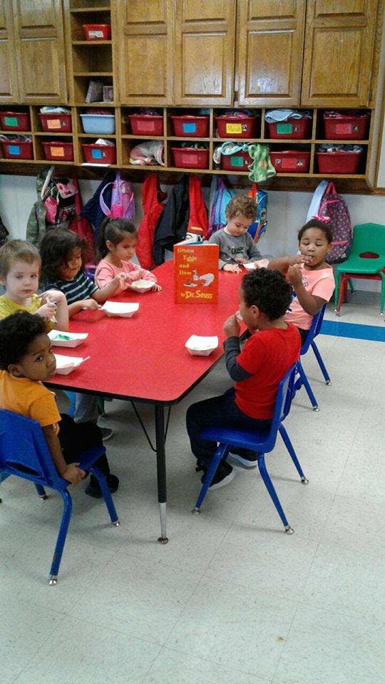 Children sitting at a red table with small white bowls
