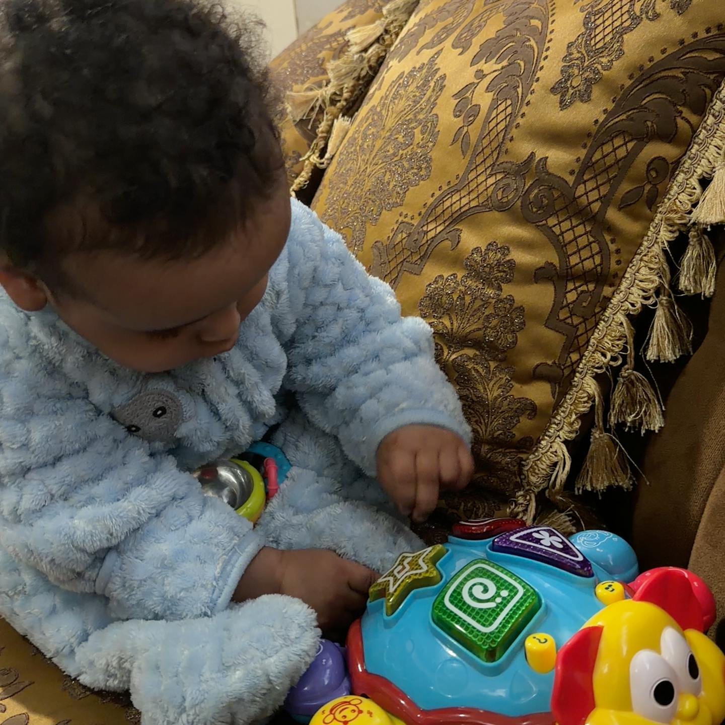 Child in a fluffy blue outfit playing with a colorful toy