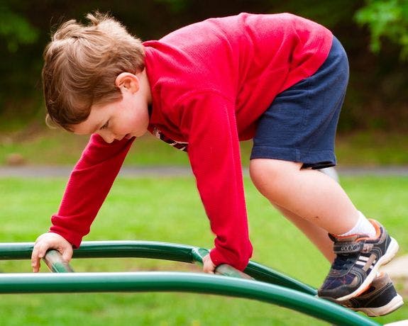 Child climbing on green playground equipment