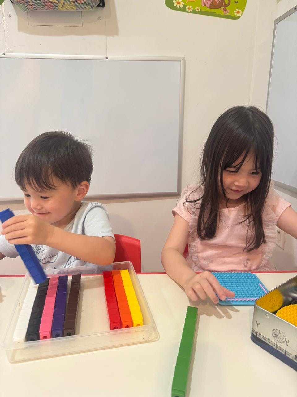 Two children playing with colorful connecting blocks at a table in a classroom