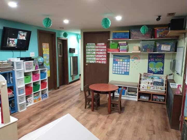 Classroom with small table and chairs, shelves with storage bins, and wall decorations
