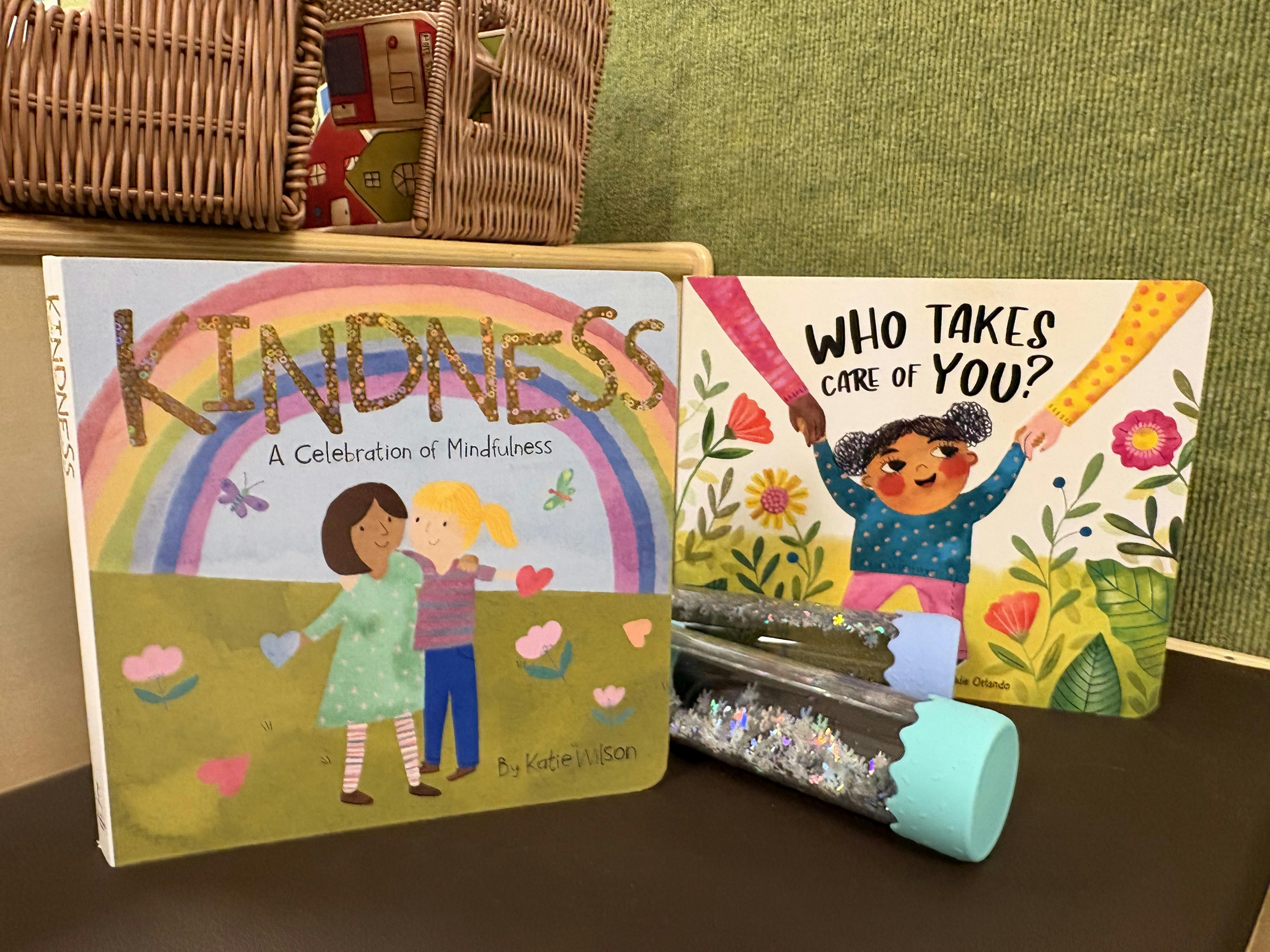 Two children's books, one titled "Kindness" and the other "Who Takes Care of You?"