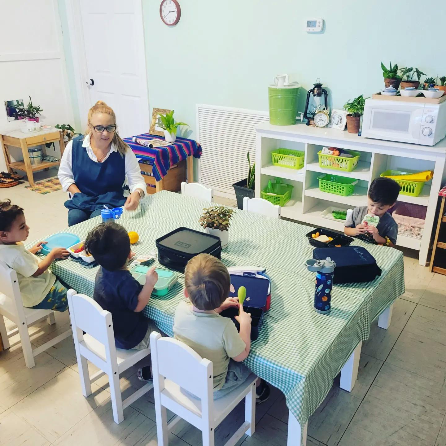 Person and children eating at a table in a classroom