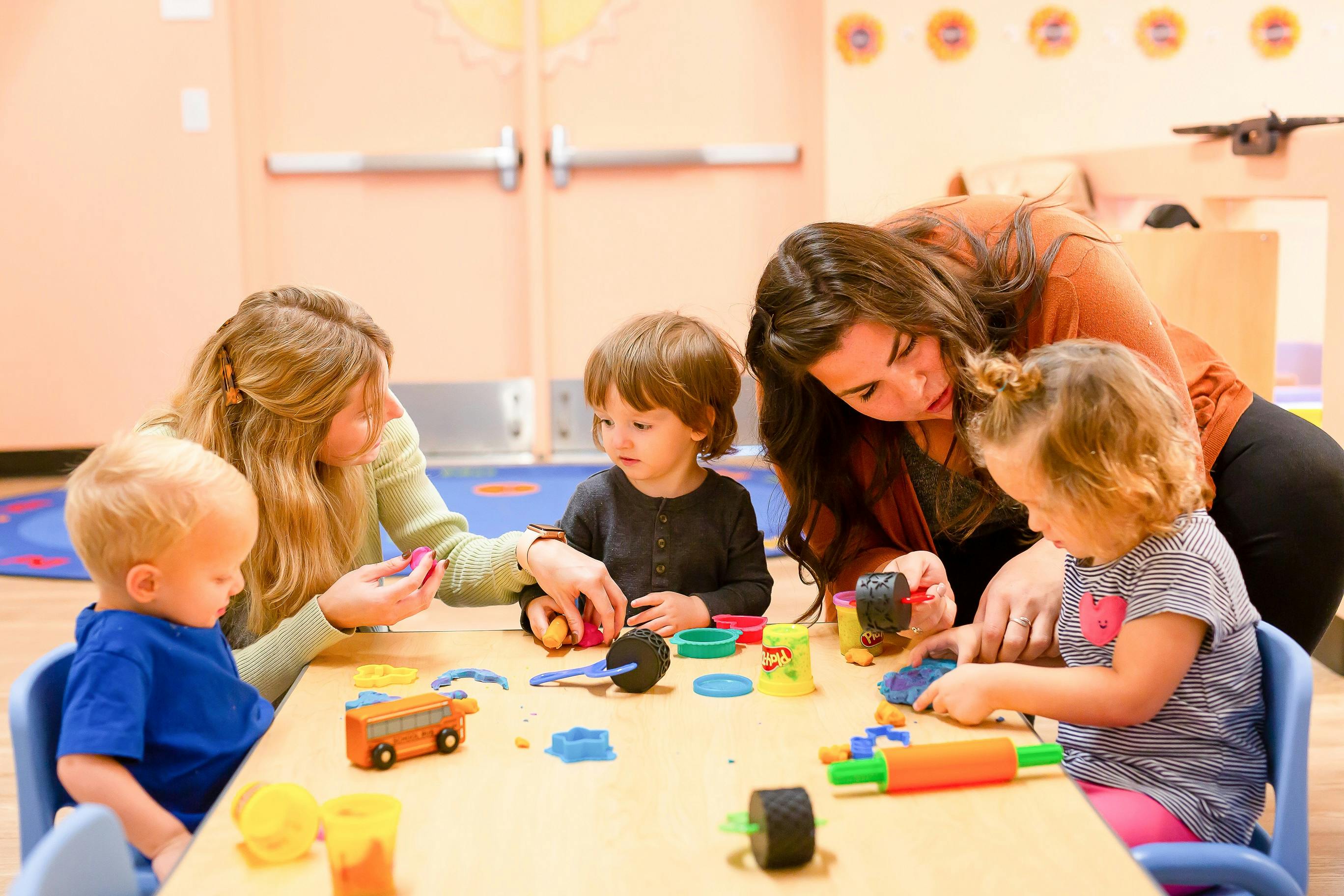 People sitting at a table and playing with modeling clay in a classroom