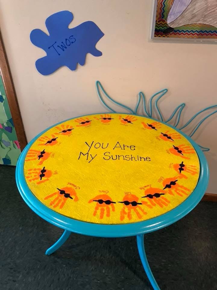 Round yellow table with handprints and "You Are My Sunshine" text