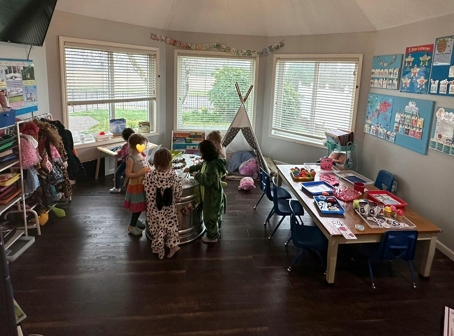 Children playing in a classroom with a teepee and tables