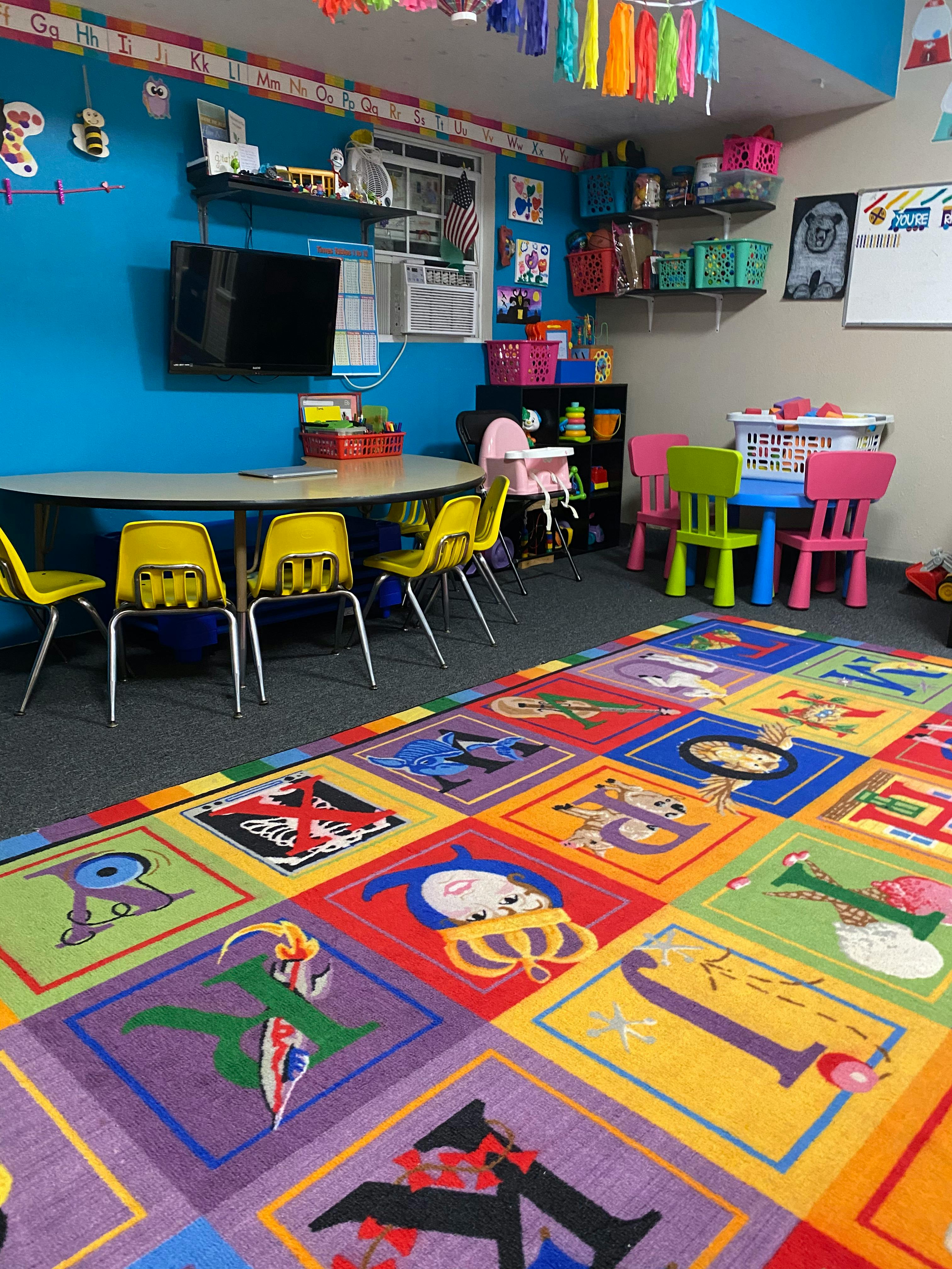 Classroom with a colorful alphabet rug, tables, and chairs
