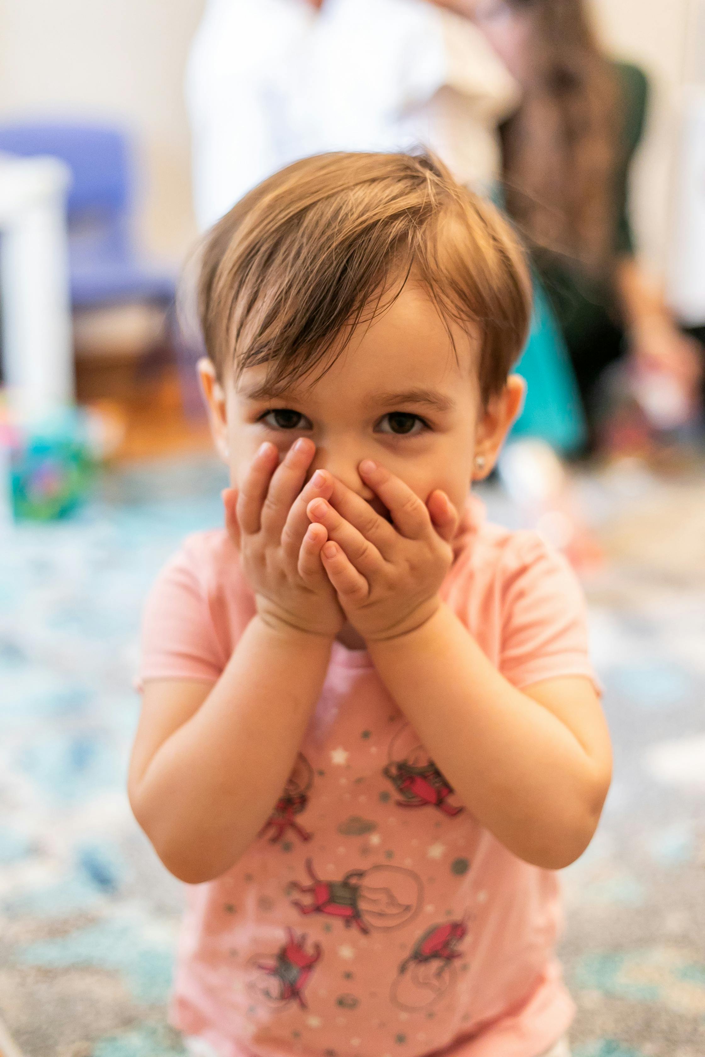 Child with hands covering mouth
