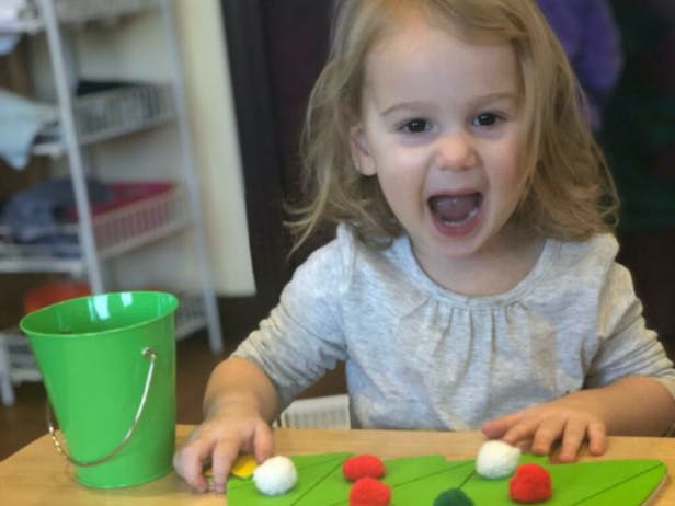 Child at a table with a green bucket and craft items