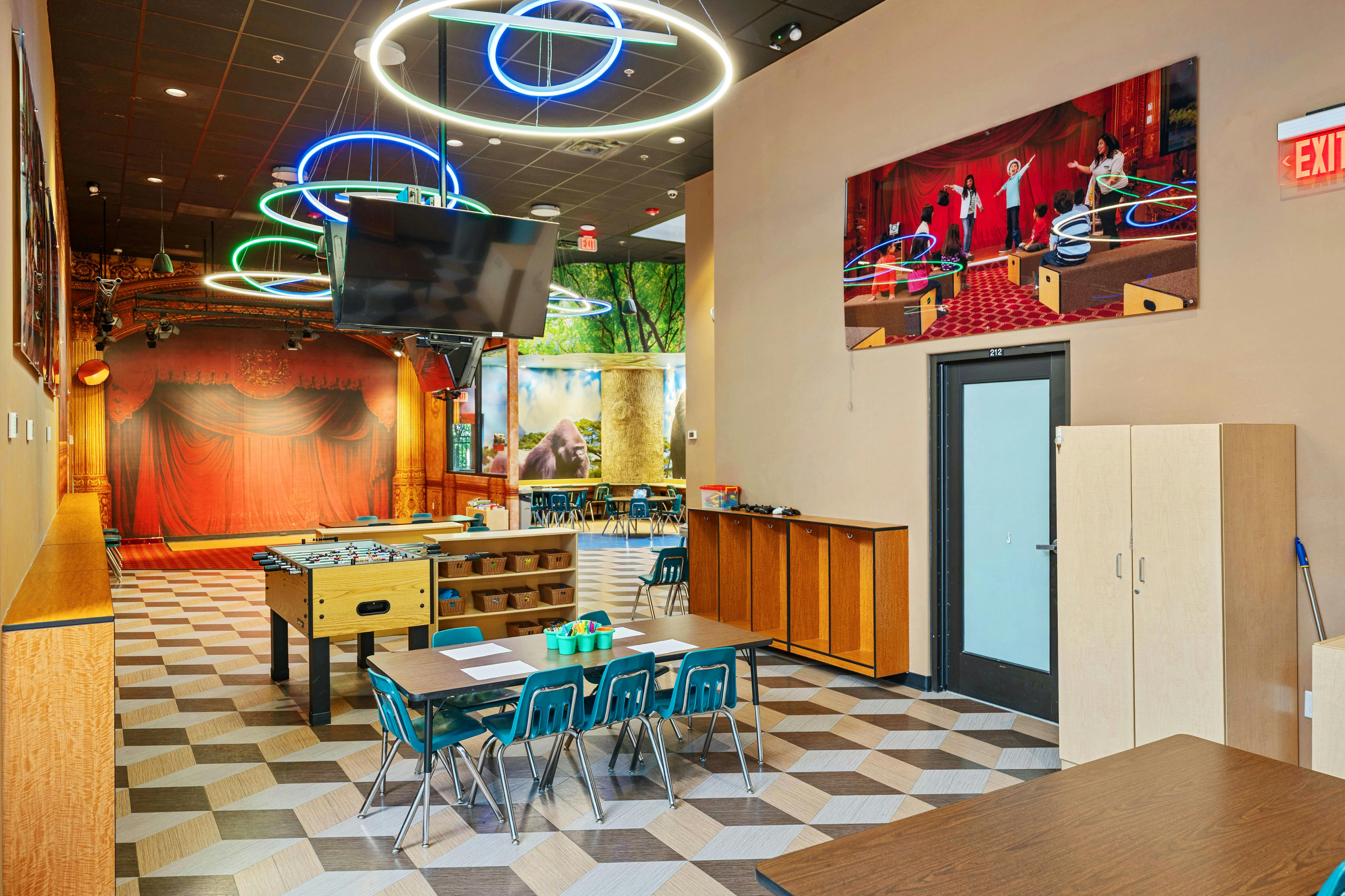 Children's activity room with a foosball table, small tables, and murals