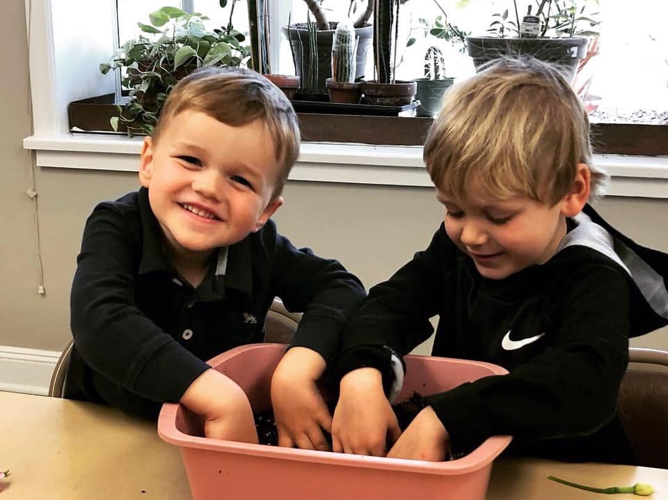 Two children playing with items in a pink bin