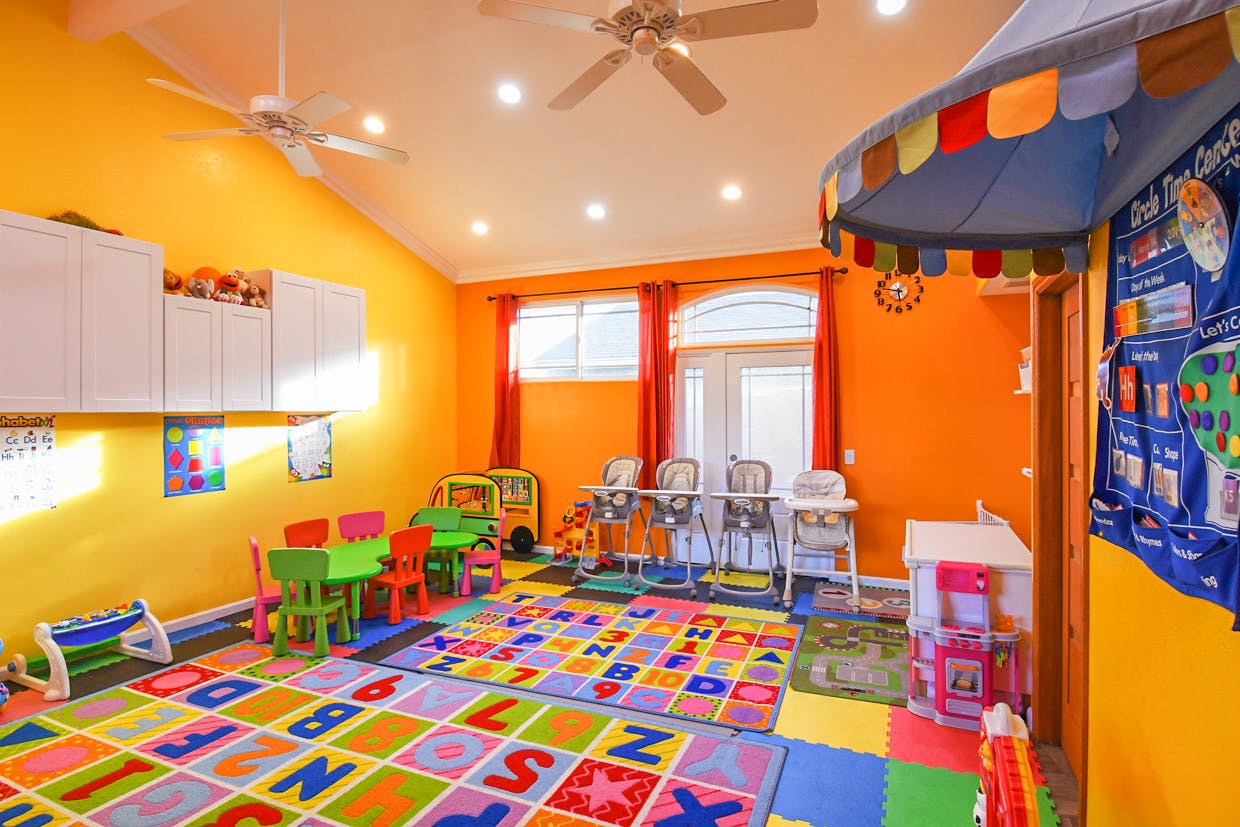 Playroom with colorful alphabet rug, small tables and chairs, and high chairs