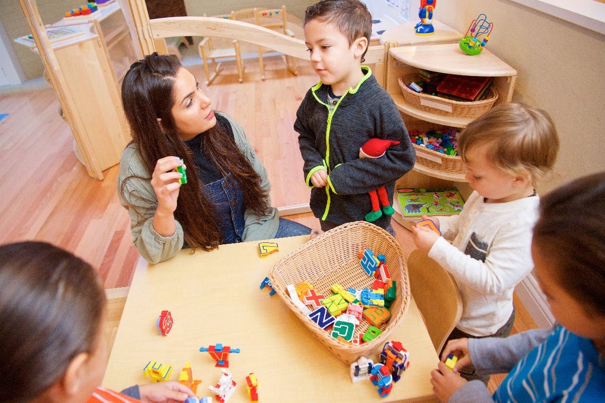 Person interacting with children at a table with toys