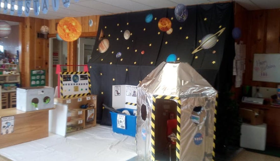 Classroom decorated with space theme, including a cardboard rocket ship