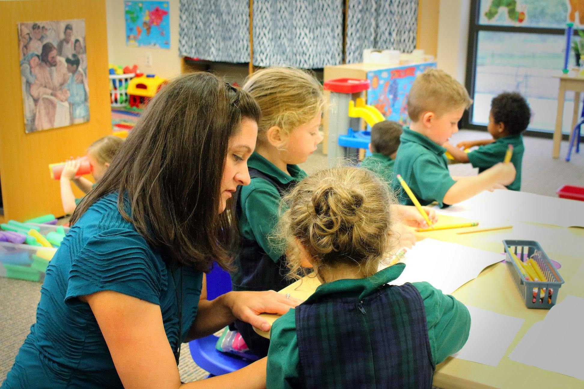 Adult and children drawing at a table in a classroom