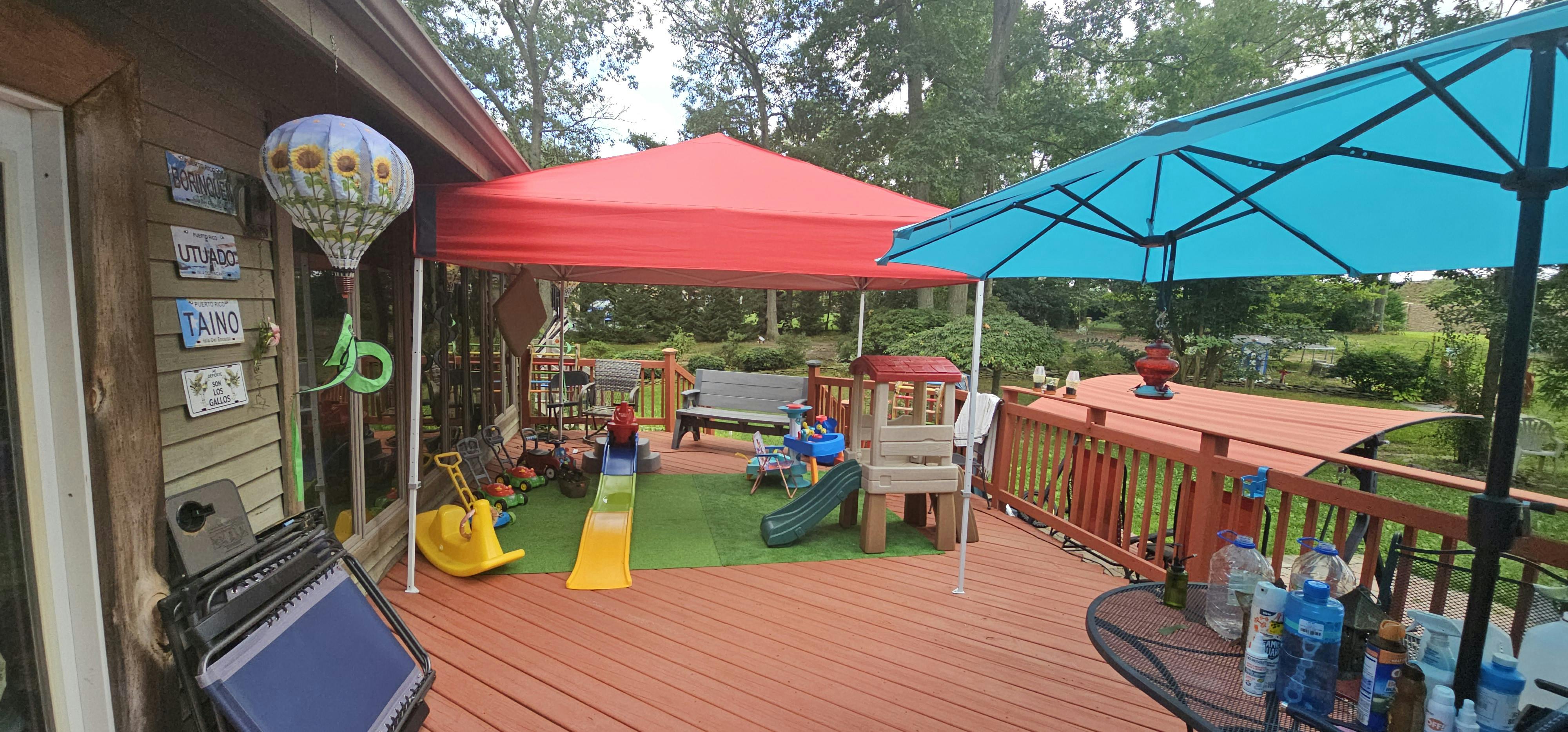 Outdoor deck with red canopy, blue umbrella, and children's play area