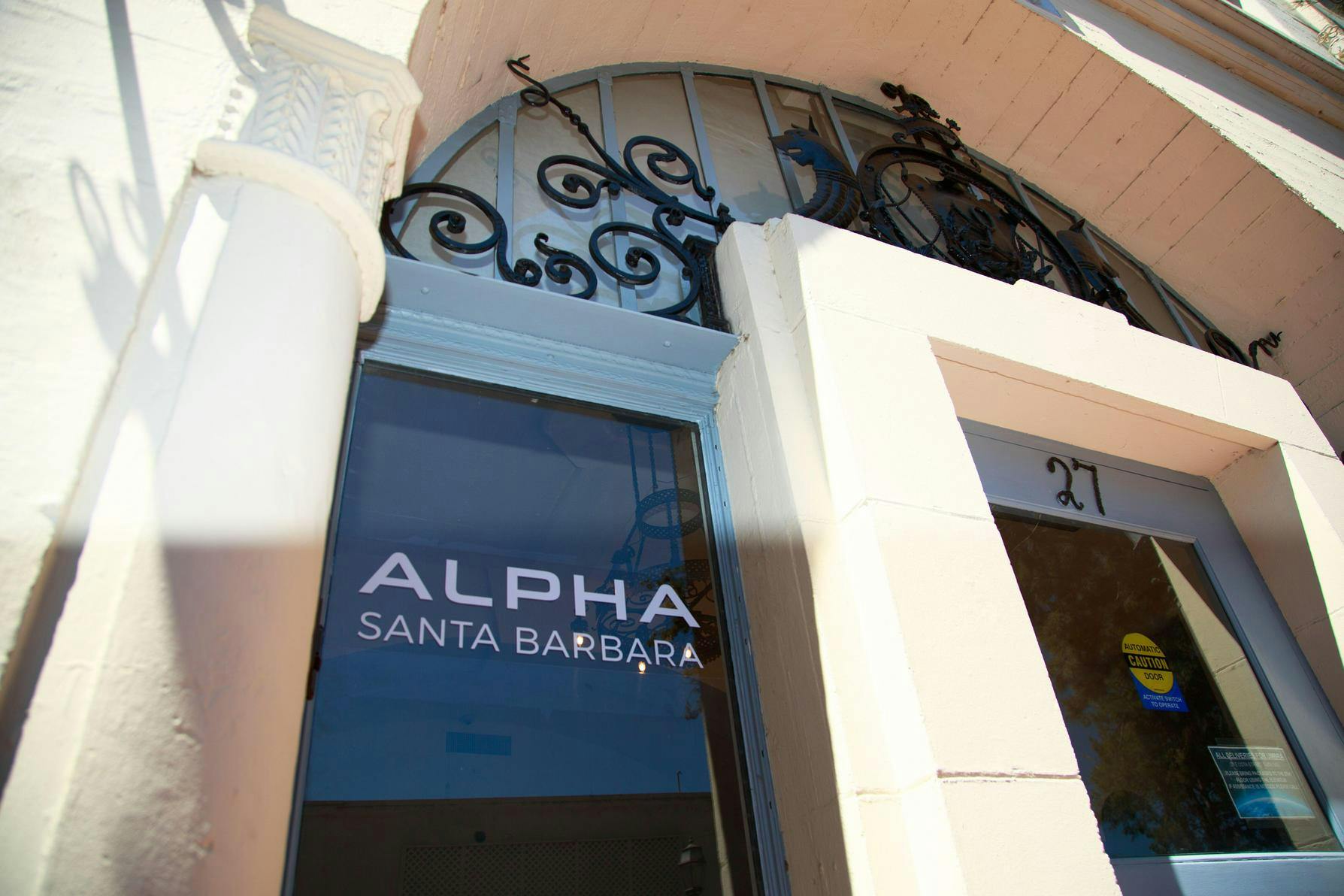 Entrance to a building with ALPHA SANTA BARBARA on the glass door