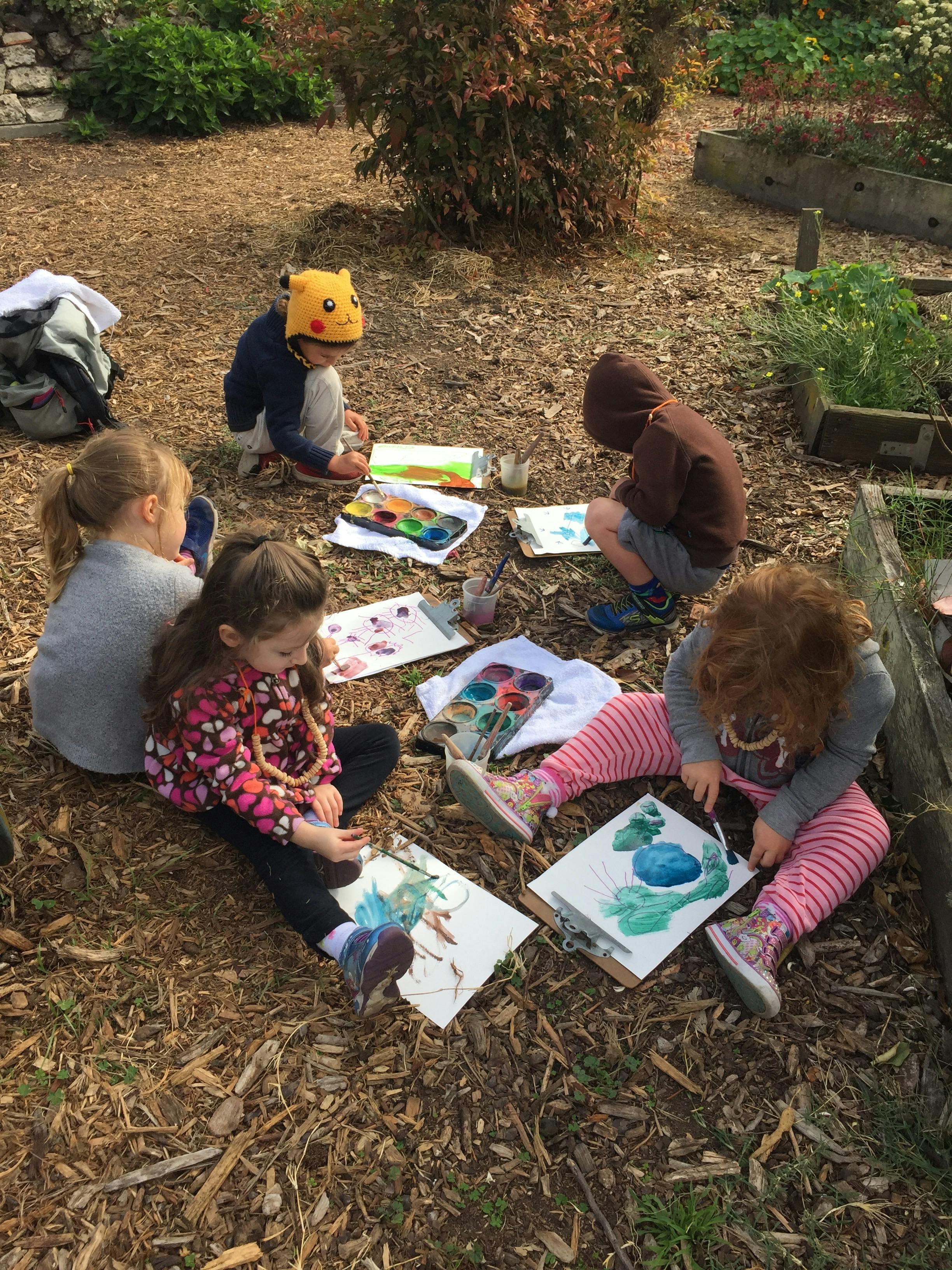 Children painting outdoors on the ground
