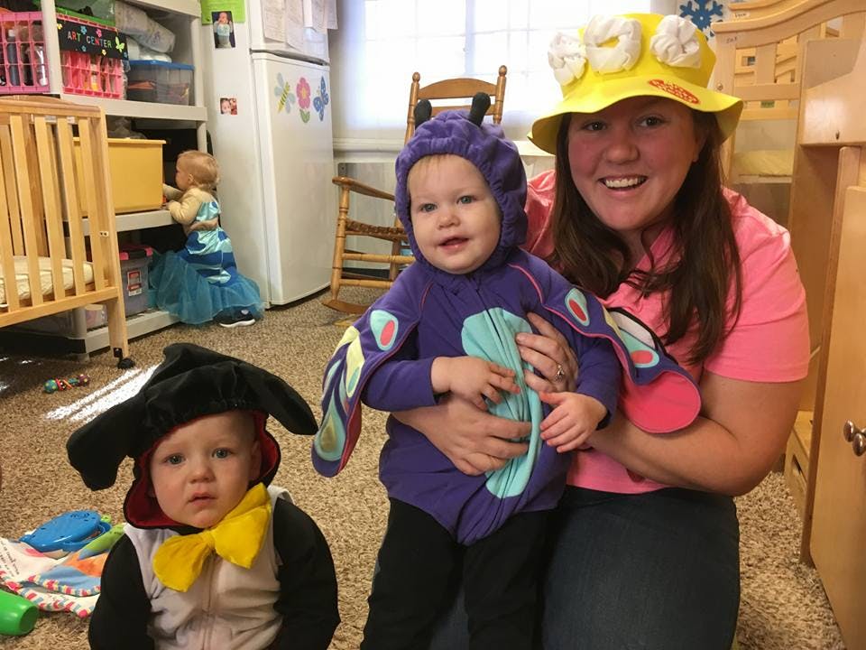 Person holding a child in a butterfly costume, another child in a penguin costume