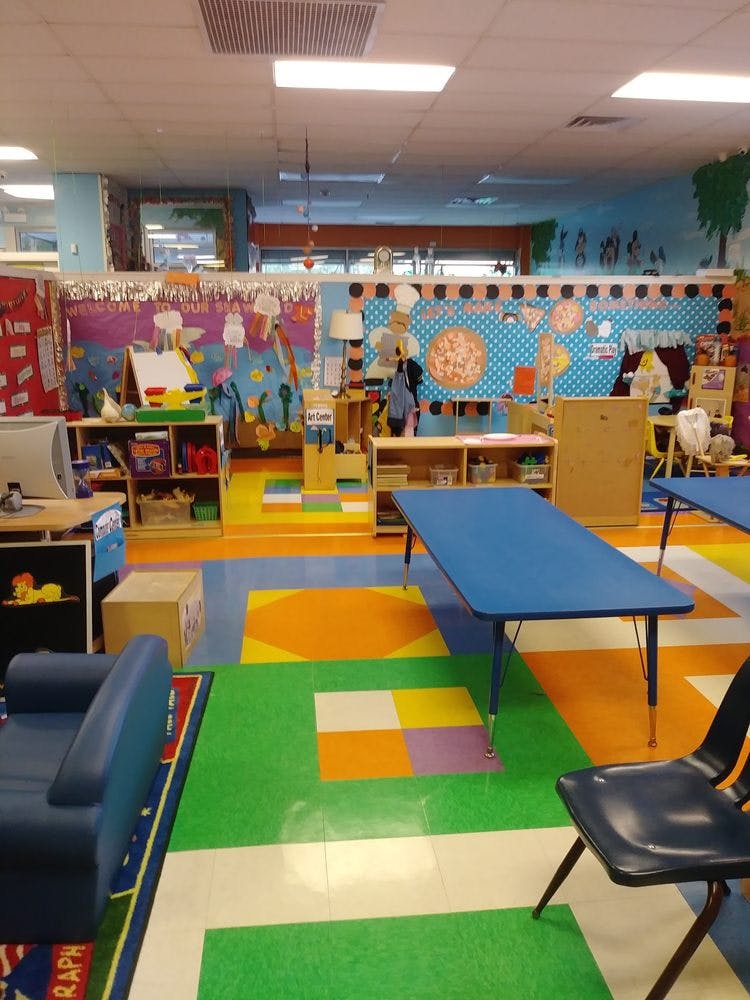 Classroom with colorful floor, blue tables, and decorated walls