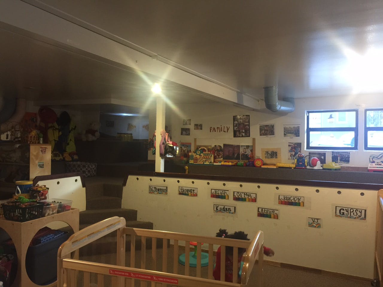 Crib and play area in a room with windows