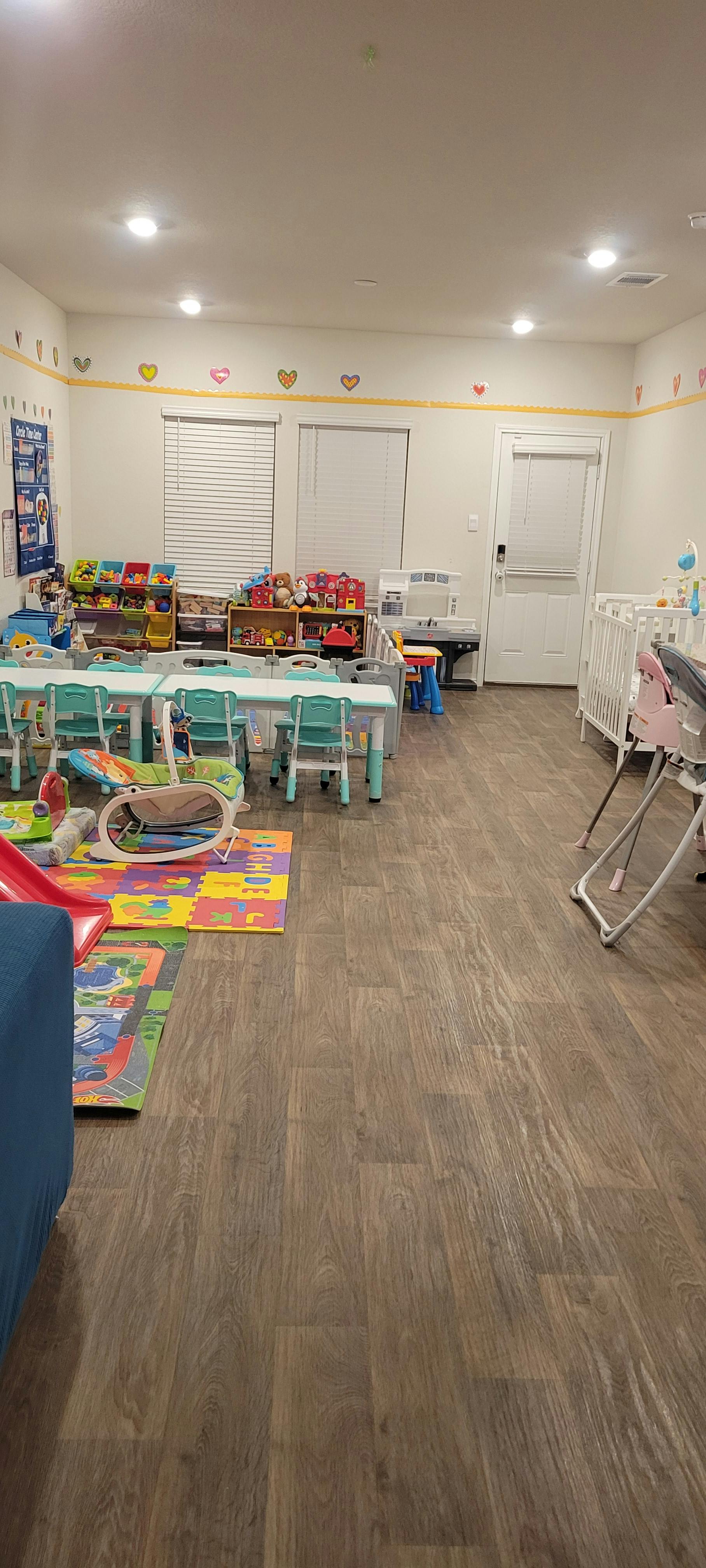 Playroom with small tables and chairs, shelves of toys, and a crib